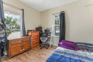 Bedroom with light wood finished floors and an office area