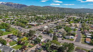 Aerial view of property and surrounding area featuring a mountainous background and nearby suburban area