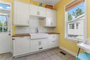 Kitchen with butcher block counters, a sink, decorative backsplash, and healthy amount of natural light