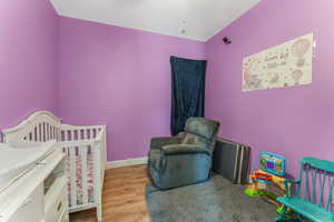 Bedroom featuring wood finished floors, a crib, and brick wall