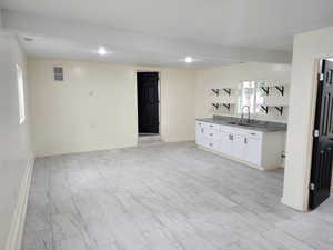 Bar with a sink, light marble finish floors, and baseboards