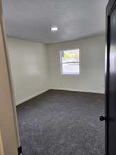 Spare room with dark carpet, baseboards, a textured ceiling, and recessed lighting