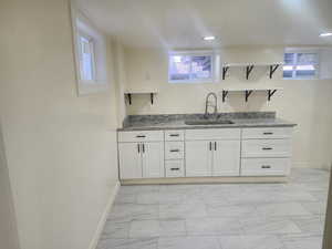 Bar with a sink, baseboards, and light marble finish flooring