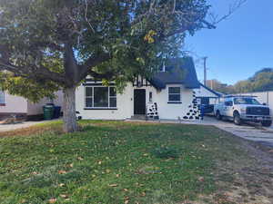 View of front of property with stucco siding, a front yard, and roof with shingles