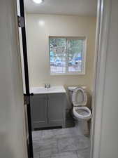 Bathroom with toilet, vanity, and marble finish flooring