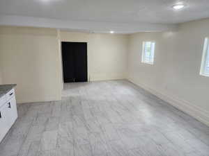 Spare room featuring a textured ceiling, baseboards, and recessed lighting