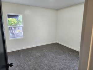 Spare room with dark colored carpet and baseboards