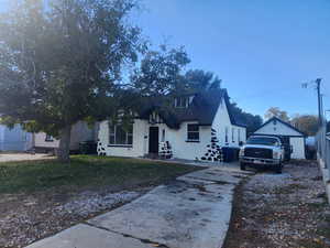 View of front of house with stucco siding, concrete driveway, a shingled roof, and an outbuilding