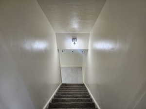 Staircase featuring a textured ceiling and baseboards