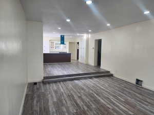 Unfurnished living room featuring wood finished floors, baseboards, and recessed lighting