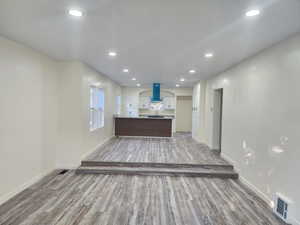 Unfurnished living room featuring light wood-type flooring, baseboards, recessed lighting, and a sink