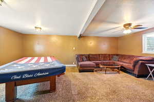 Recreation room featuring carpet, a ceiling fan, baseboards, and a textured ceiling