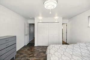 Bedroom featuring a closet, ornamental molding, baseboards, and dark wood-style floors