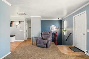 Tiled entryway with carpet floors, ornamental molding, and baseboards