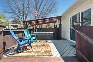Wooden terrace featuring a hot tub, fence, and a pergola