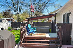 Wooden terrace featuring a hot tub, a fenced backyard, and area for grilling