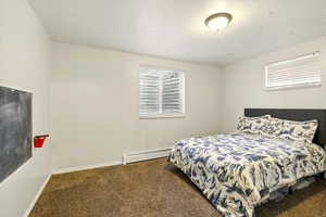 Carpeted bedroom featuring a baseboard radiator and baseboards