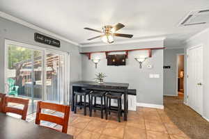 Dining area with crown molding, a ceiling fan, light tile patterned floors, and baseboards