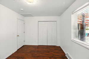 Unfurnished bedroom with wood finished floors, multiple windows, a closet, and attic access