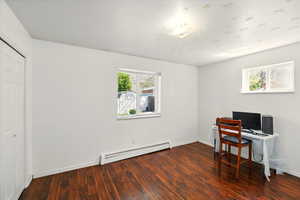 Home office with baseboard heating, healthy amount of natural light, wood finished floors, and baseboards