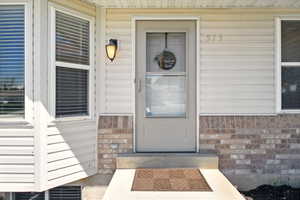 View of exterior entry featuring brick siding and a porch