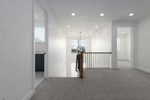 Hall featuring carpet, recessed lighting, an upstairs landing, and baseboards