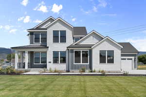View of front of house featuring board and batten siding, covered porch, a front lawn, and an attached garage