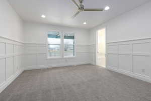Carpeted spare room with a decorative wall, a ceiling fan, a wainscoted wall, and recessed lighting