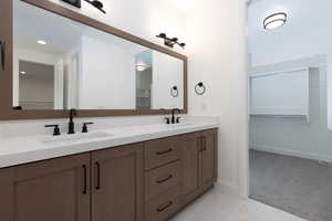 Full bathroom with double vanity, baseboards, a spacious closet, and recessed lighting