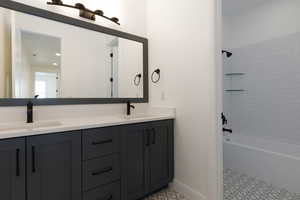Full bathroom with double vanity, shower / washtub combination, baseboards, and tile patterned floors