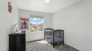 Bedroom with carpet floors, baseboards, and a crib