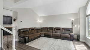 Living area featuring wood finished floors, baseboards, healthy amount of natural light, and lofted ceiling