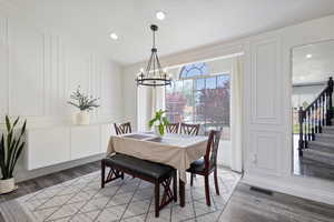 Dining space with a chandelier, plenty of natural light, a decorative wall, light wood finished floors, and recessed lighting