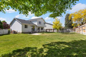 Rear view of house featuring a trampoline, central air condition unit, and a patio