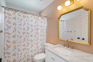 Bathroom with toilet, vanity, and a shower with shower curtain