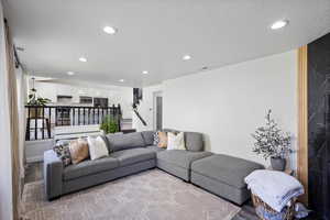 Living room with recessed lighting, light wood-style flooring, stairway, and a textured ceiling