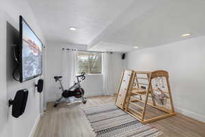 Exercise area with a textured ceiling, baseboards, wood finished floors, and recessed lighting