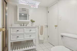 Bathroom featuring toilet, tile patterned flooring, a shower stall, and vanity