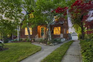 View of front of property with an outbuilding, concrete driveway, a detached garage, a front lawn, and covered porch