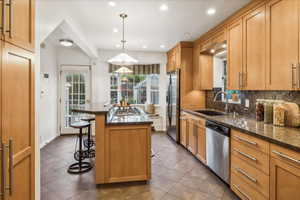 Kitchen featuring stainless steel appliances, a sink, a kitchen island, a breakfast bar area, and tasteful backsplash