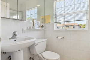 Bathroom featuring tile walls and toilet