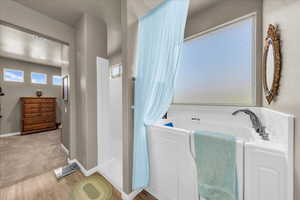 Bathroom with wood finished floors, a bath, and baseboards