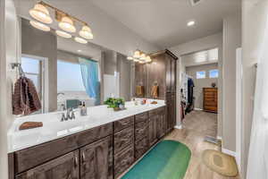 Full bathroom with wood finished floors, double vanity, and baseboards