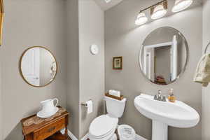 Bathroom featuring toilet, a sink, and baseboards