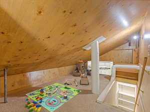 Playroom with lofted ceiling, carpet flooring, wooden walls, and wood ceiling
