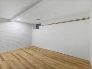 Finished basement featuring wood finished floors and brick wall