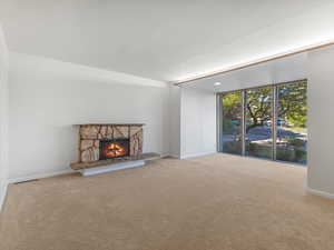 Unfurnished living room with a fireplace, carpet floors, and baseboards