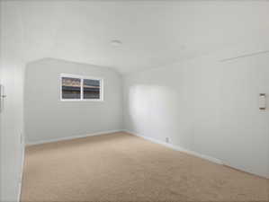 Spare room with carpet floors, vaulted ceiling, and baseboards