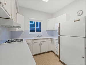 Kitchen featuring white appliances, a sink, light countertops, and white cabinets