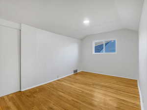 Additional living space featuring light wood-style flooring and vaulted ceiling